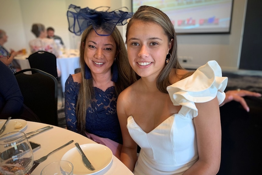Two women dressed up, one wearing a fascinator