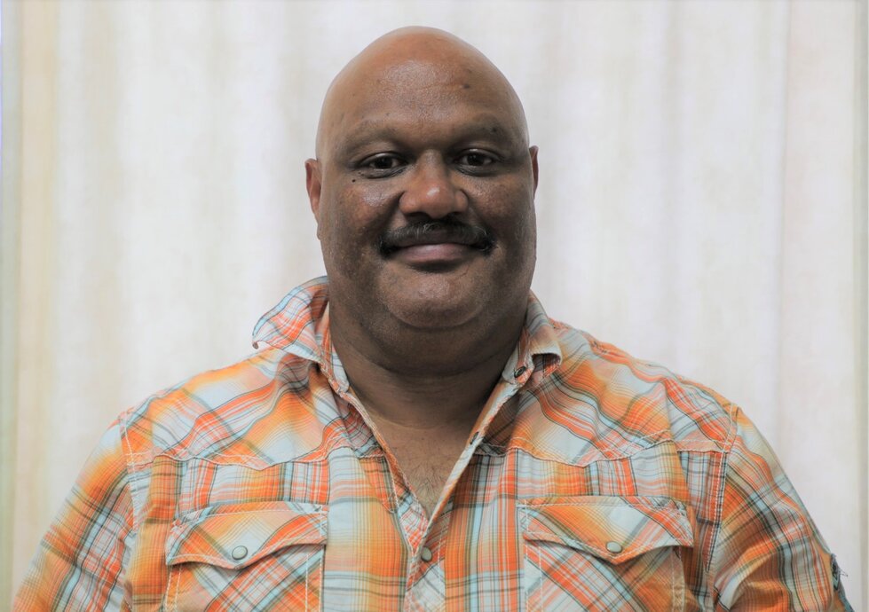 A man in a dress shirt smiles at the camera.