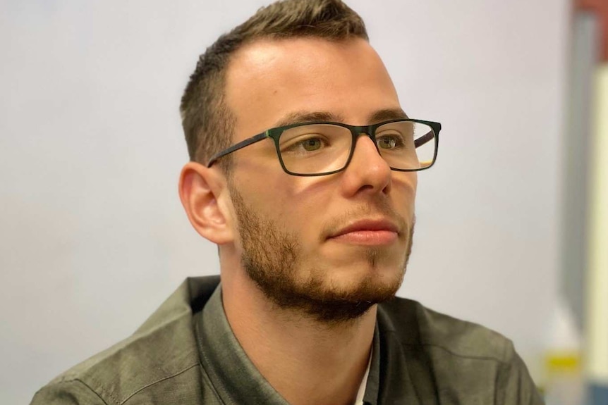 A headshot of a young man with glasses wearing a shirt with Murdoch University on it.