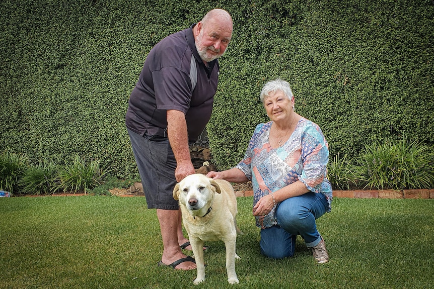 Dale and Barbara pose for a photo in their backyard with their pet labrador.
