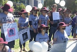 Protesters wearing t-shirts with various slogans written on them, with some people with tape on mouths and holding signs.