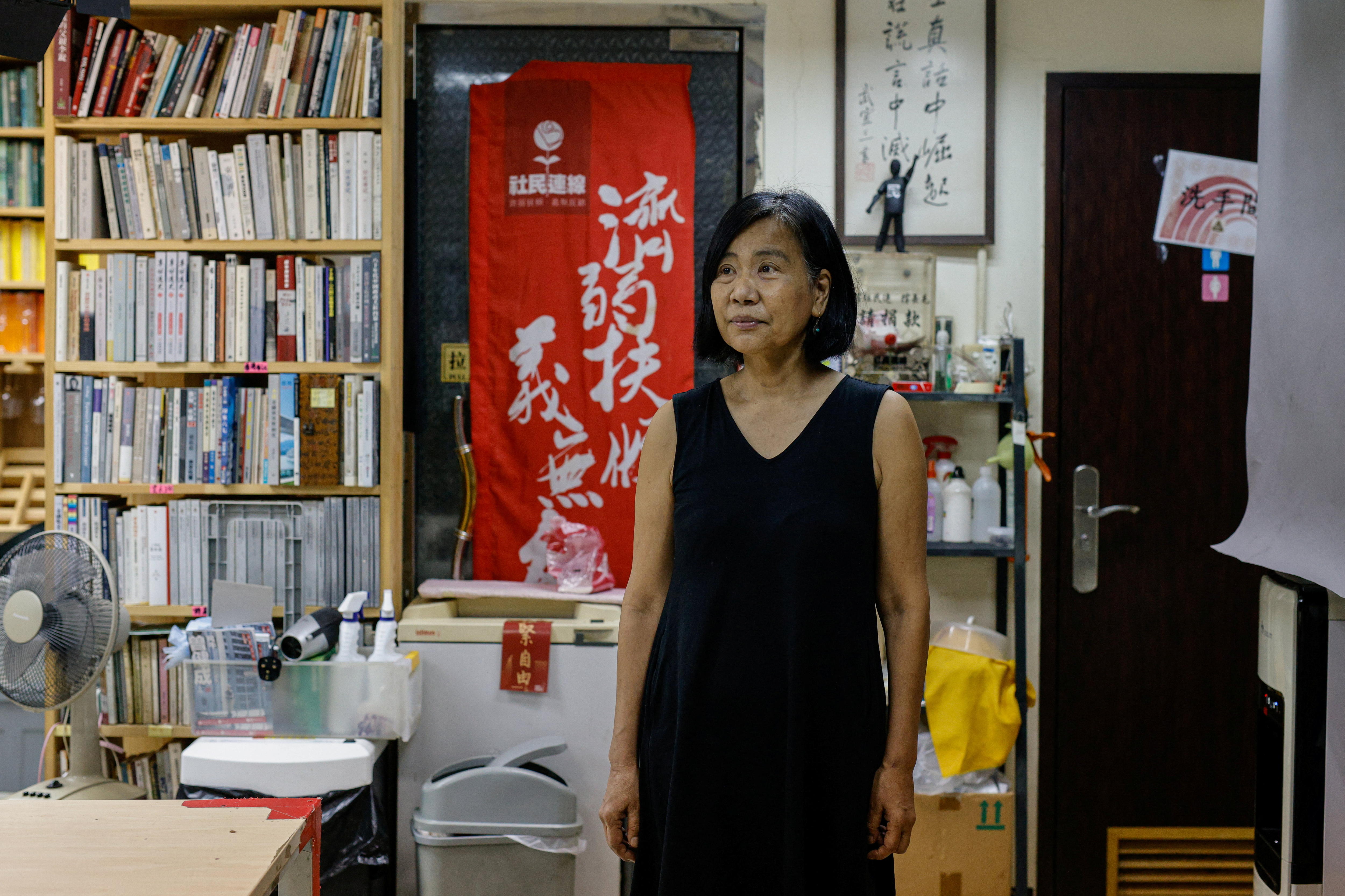 A woman in a black dress with cropped hair stands in an office