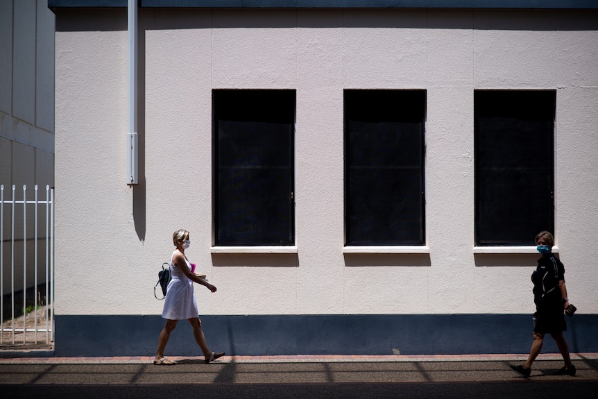 A woman walking down a street in Darwin during a COVID-19 lockdown in the city