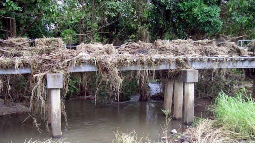 Debris left behind from the floodwaters caused by Cyclone Ellie hangs from a cane rail bridge