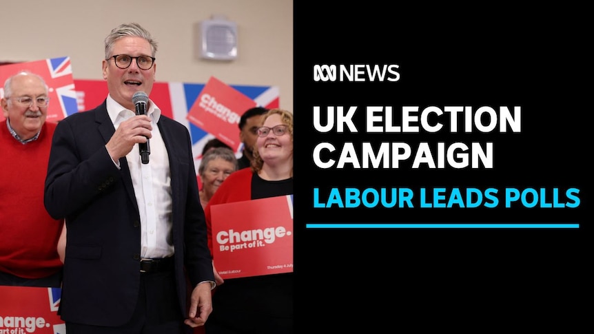 UK election campaign, Labour Leads Polls: Man in suit without tie stands in front of red campaign signs.