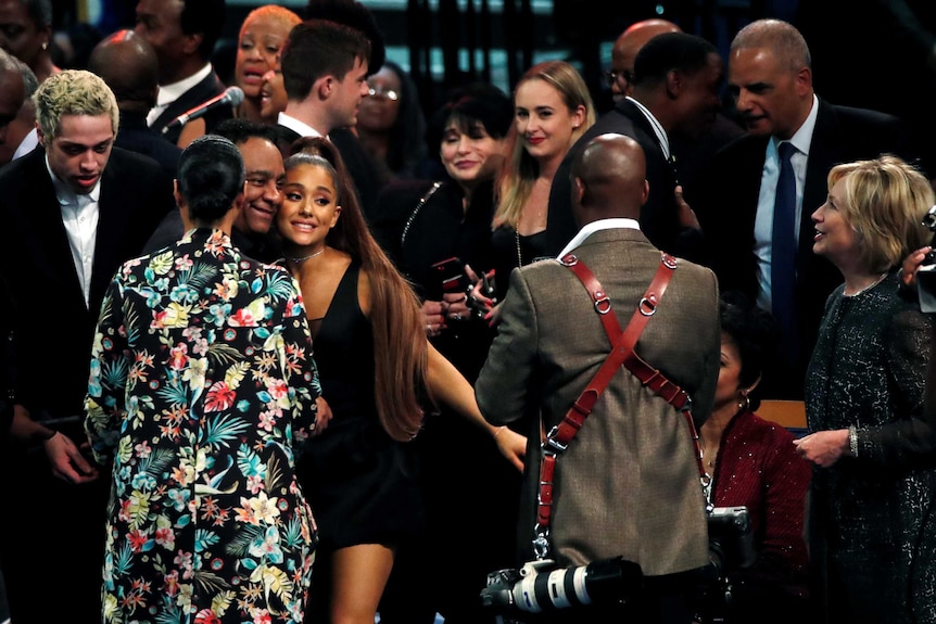 Ariana Grande poses for a photograph as Hillary Clinton and other guests look on.