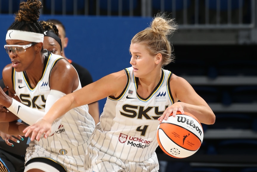 WNBA player dribbling the ball with a teammate running beside her