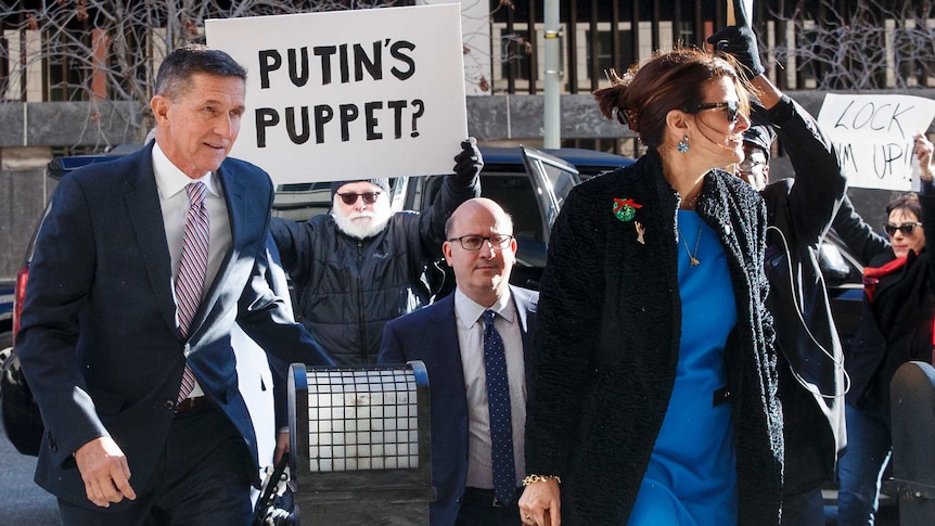 Former  National Security Advisor Michael Flynn arrives at court with protester holding sign saying Putin's Puppet?