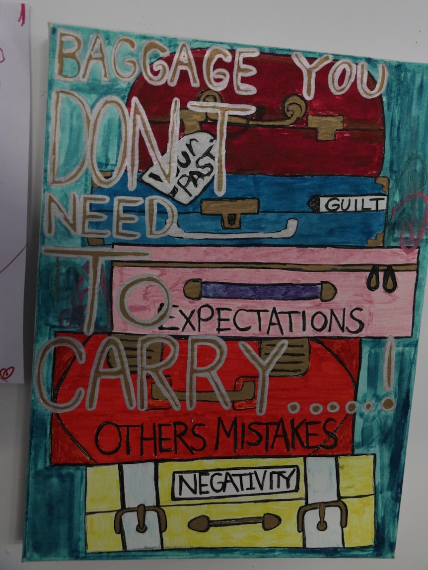 A painting of suitcases stacked on each other with the words "Baggage you don't need".