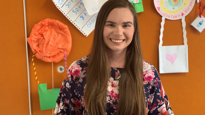 A woman with long brown hair smiles to the camera.