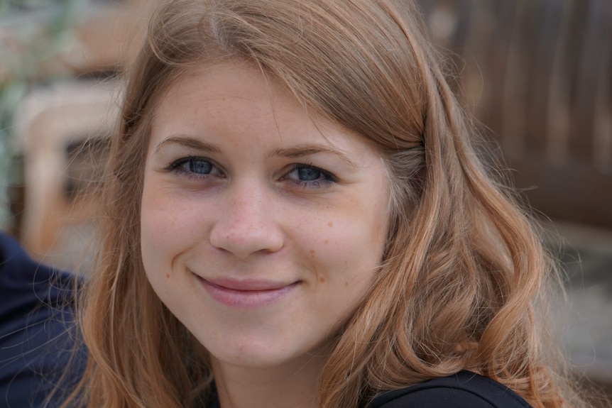 A white woman with light brown hair smiles for the camera.