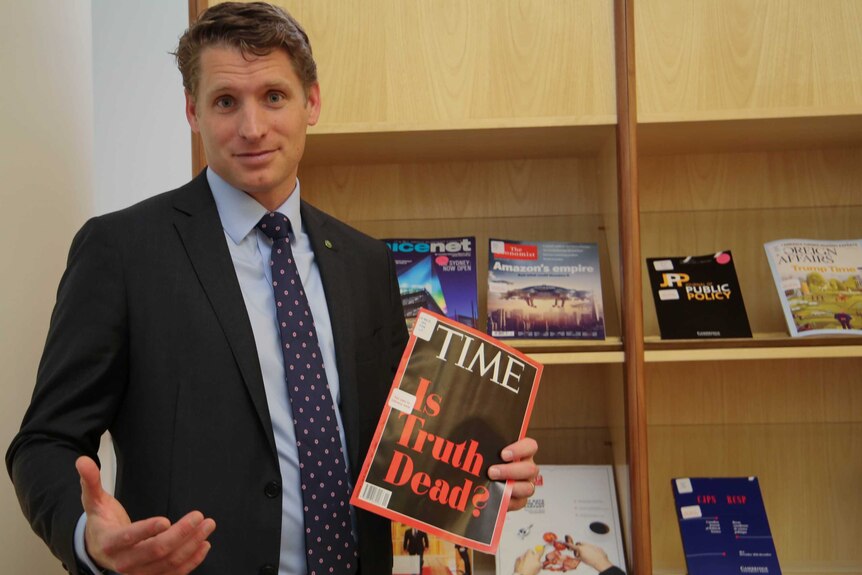 Andrew Hastie holds up an edition of Time magazine with the headline, "Is Truth Dead?"