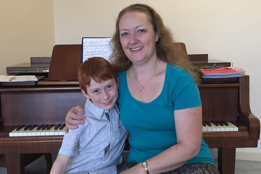 Ethan and his mum Kylie near a piano.