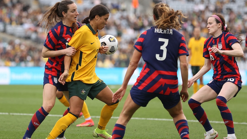 Australia's Sam Kerr with ball and surrounded by USA players during a match