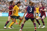 Australia's Sam Kerr with ball and surrounded by USA players during a match