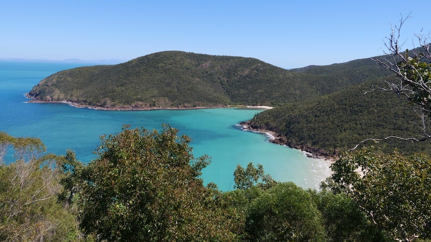 a beautiful island with white sand, crystal blue water and rolling hills