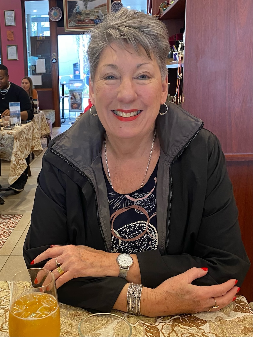 Pamela Rowland, an older white woman with short grey hair,  sitting at a table in a restaurant