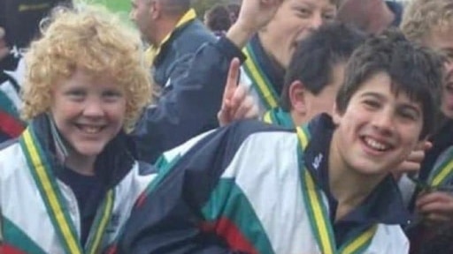 Two junior Australian rules players celebrate winning a match.