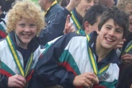 Two junior Australian rules players celebrate winning a match.