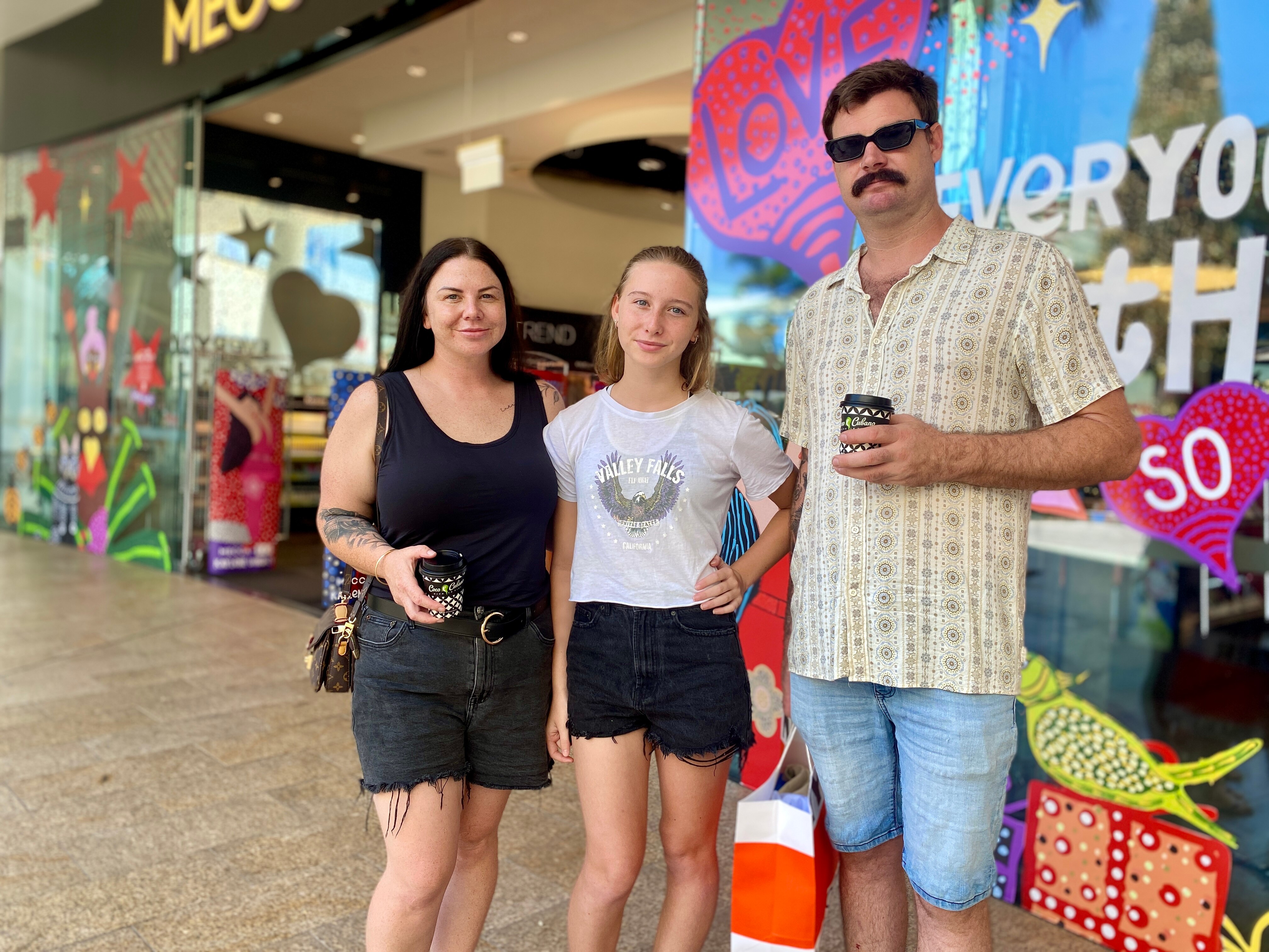 A young girl stands with her parents outside a makeup and skincare retailer.