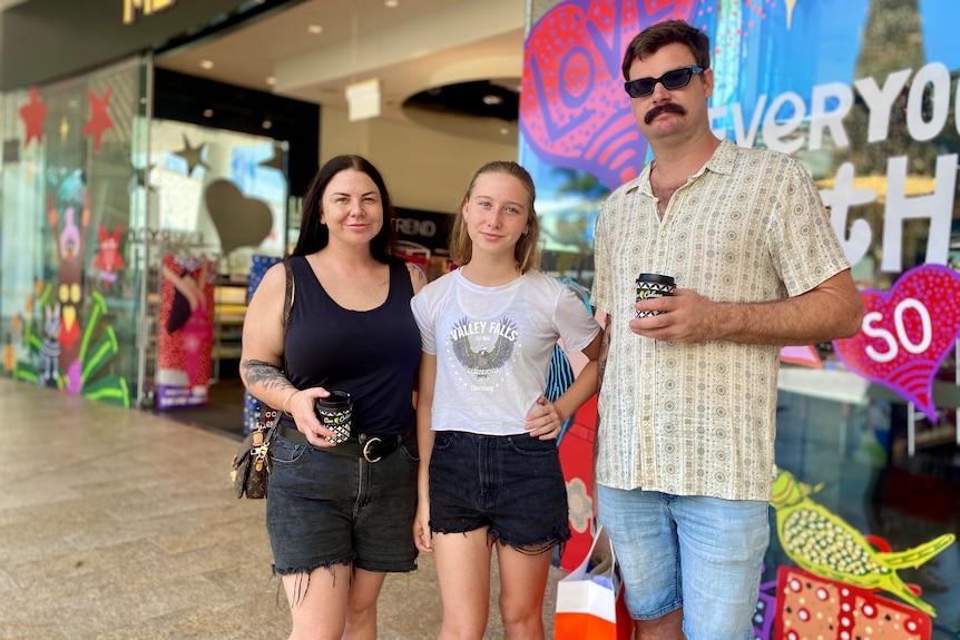 A young girl stands with her parents outside a makeup and skincare retailer.