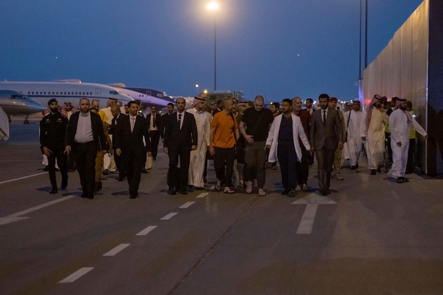 People walk on airport tarmac.