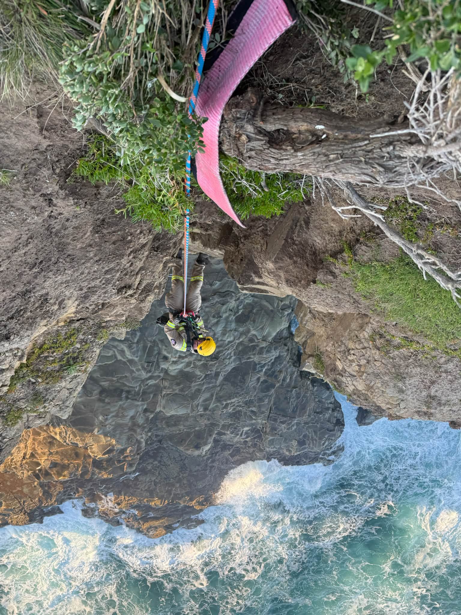 Looking down at a man in a harness abseiling down a cliff