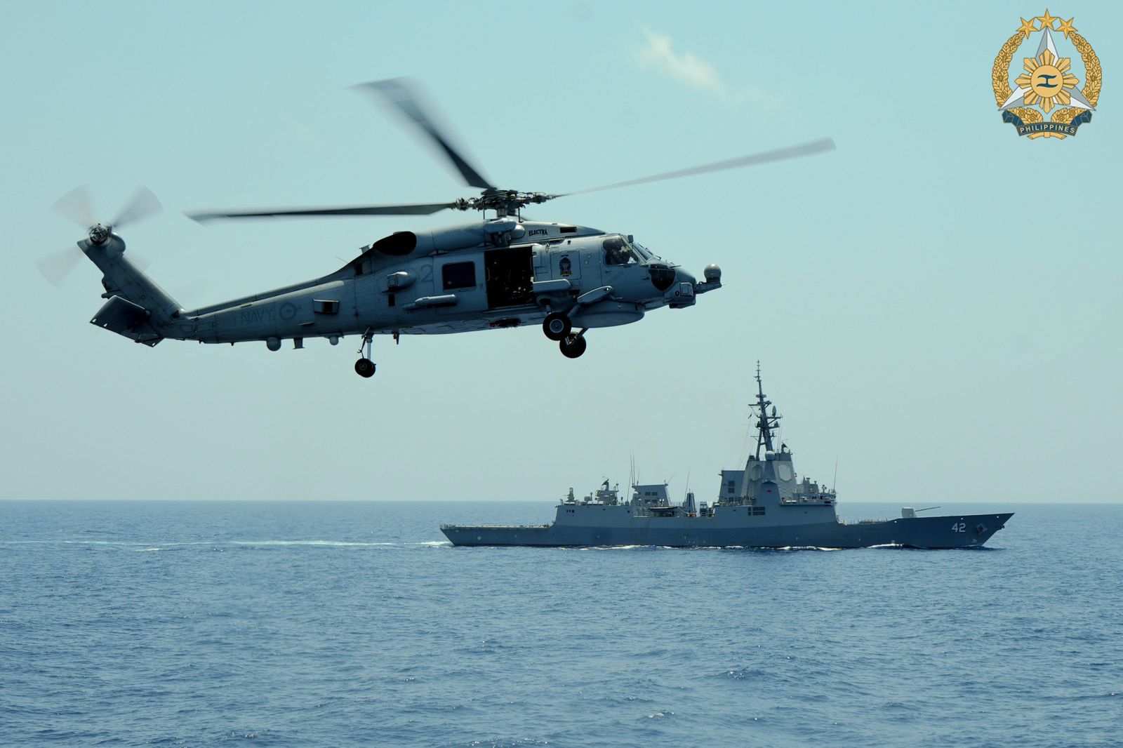 A Philippine Navy AW159 helicopter with the the HMAS Sydney in the background. 