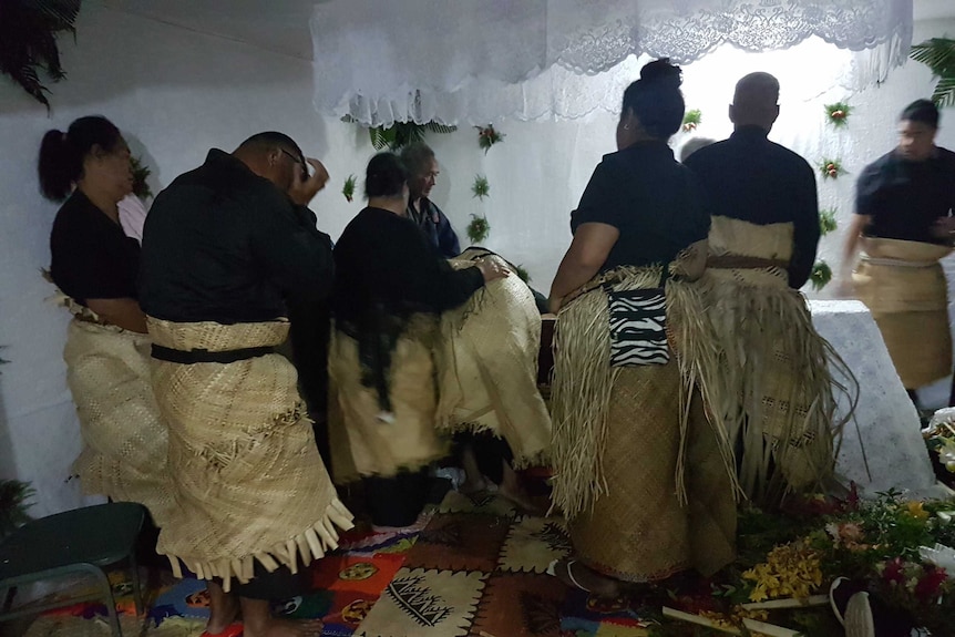 Tongan men and women in traditional thatched skirt dress in mourning at a funeral, Tonga
