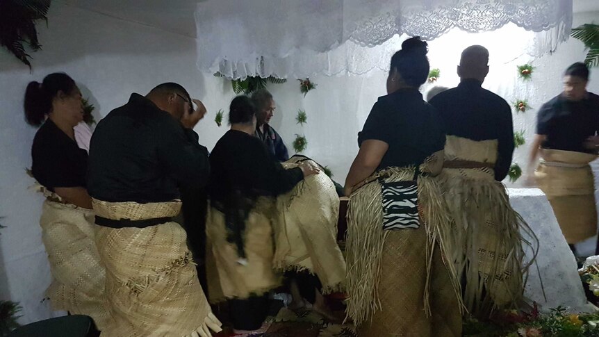 Tongan men and women in traditional thatched skirt dress in mourning at a funeral, Tonga