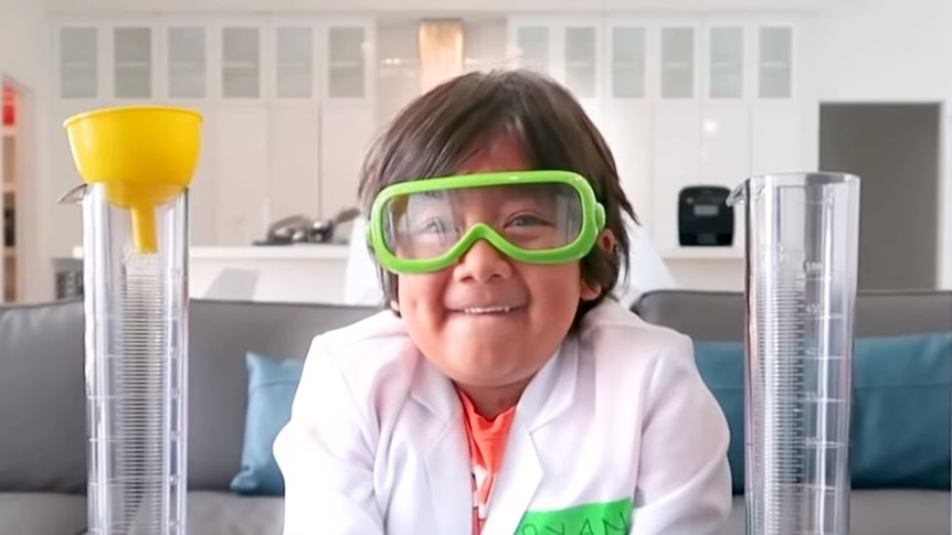 A boy smiles in goggles while doing a science experiment