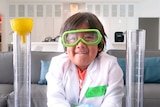 A boy smiles in goggles while doing a science experiment