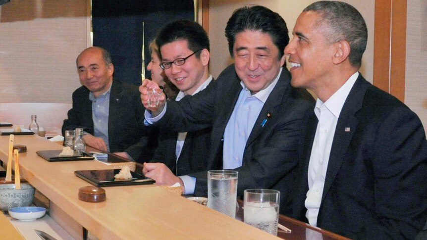 Shinzo Abe holds aloft a glass as Barack Obama smiles