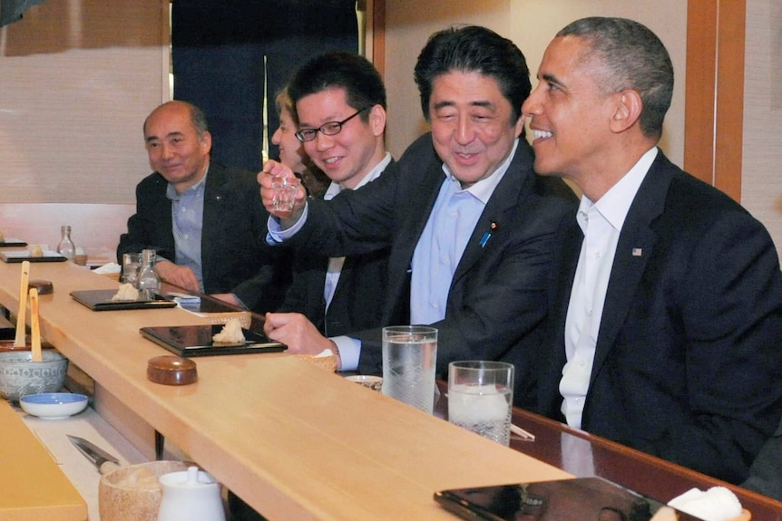 Shinzo Abe holds aloft a glass as Barack Obama smiles