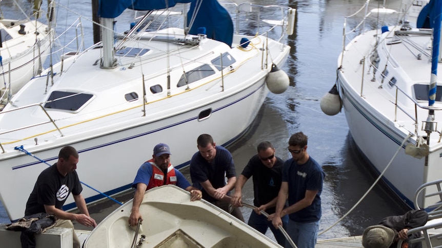 People pull a boat out of the water in the USA after a tsunami surge