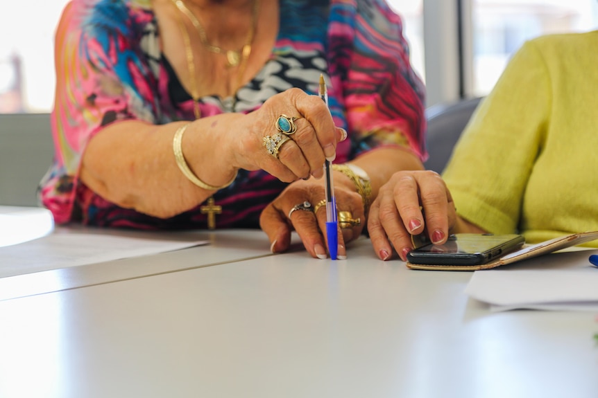 A close-up shot of a woman's hands as she taps a pen on a table