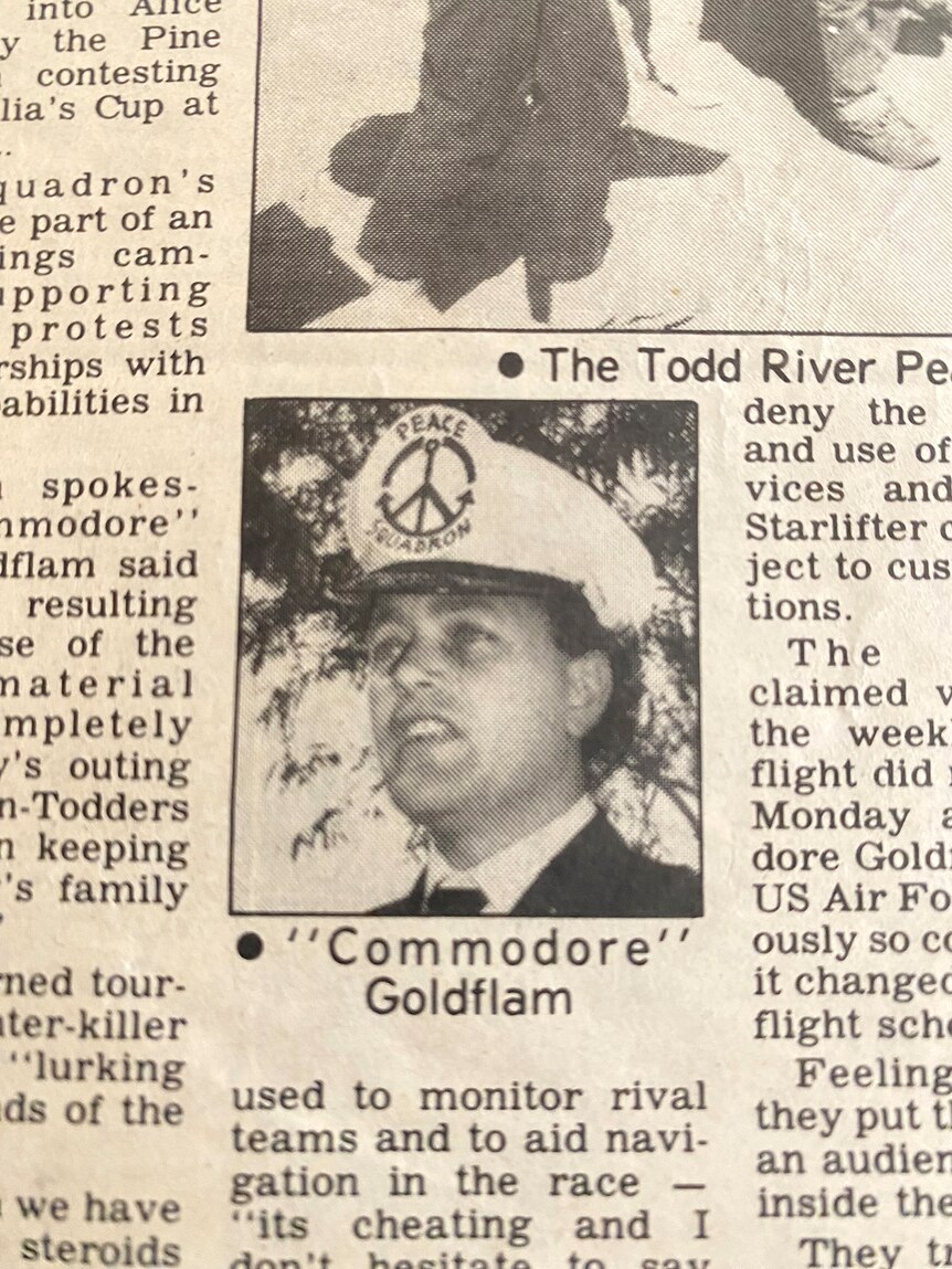 A newspaper clipping of a man wearing a sailing hat with a peace sign on its front 
