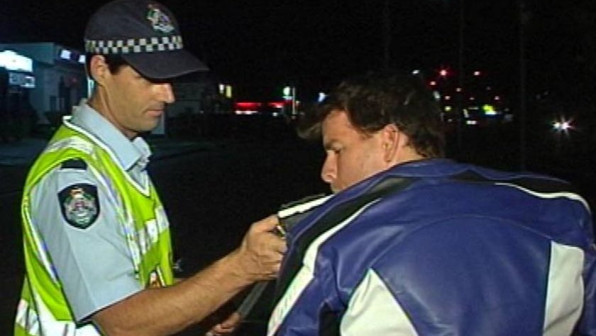 Qld police officer taking an RBT sample from a male motorcyclist