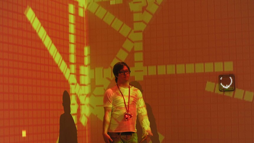 Actor Lydian Dunbar stands on stage surrounded by orange and yellow light