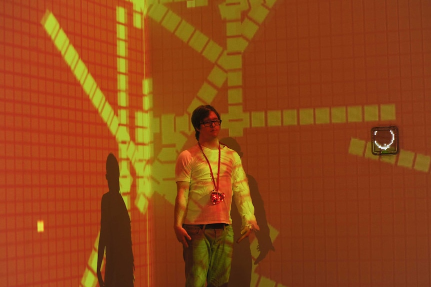 Actor Lydian Dunbar stands on stage surrounded by orange and yellow light