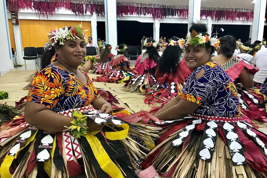 Women dressed in colourful traditional costumes with flowers in their hair.