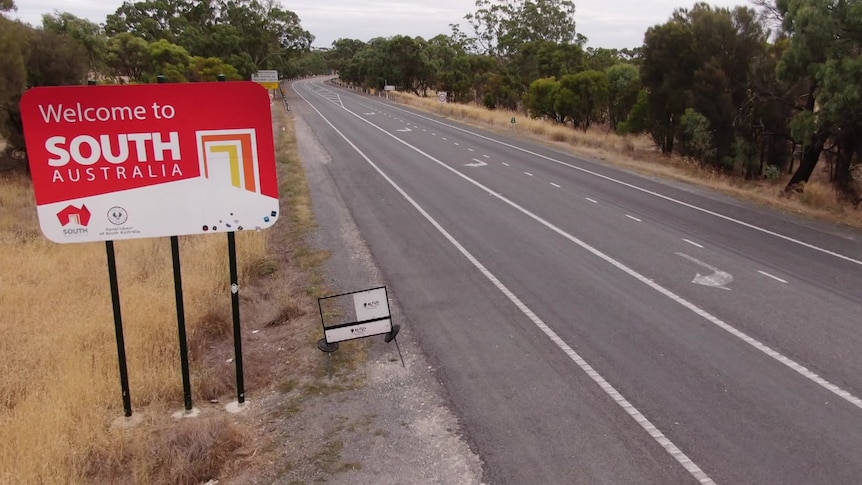 A sign saying "welcome to South Australia' in a drone shot of a road