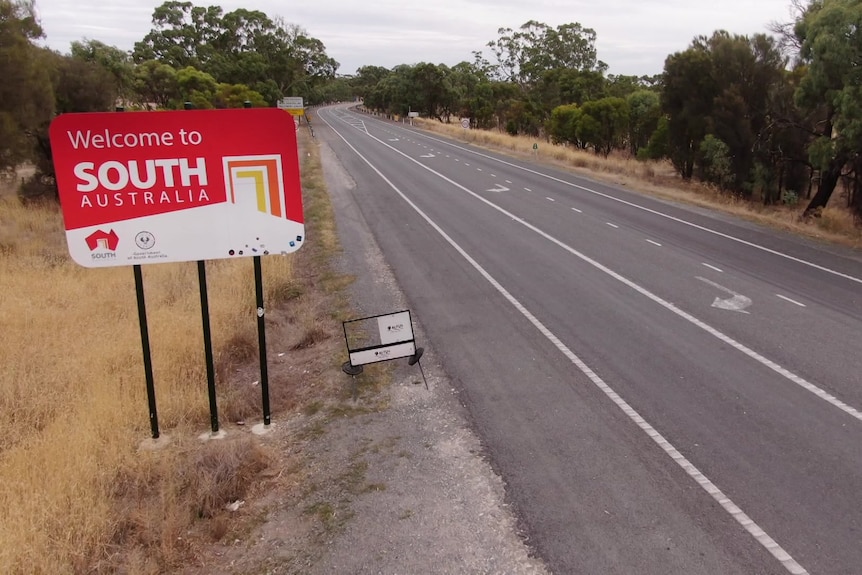 A sign saying "welcome to South Australia' in a drone shot of a road