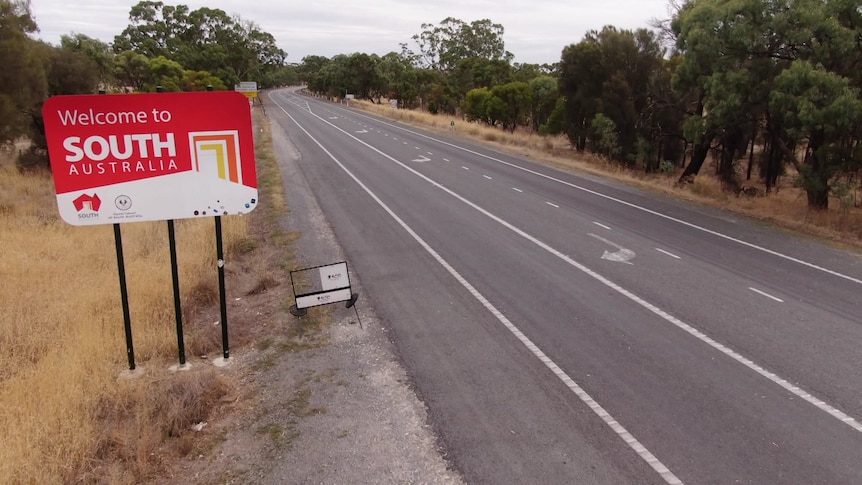 A sign saying "welcome to South Australia' in a drone shot of a road