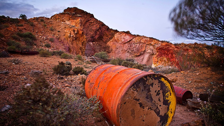 A rusting and old 44 gallon drum rests abandoned in the denuded landscape of the ex-mine.