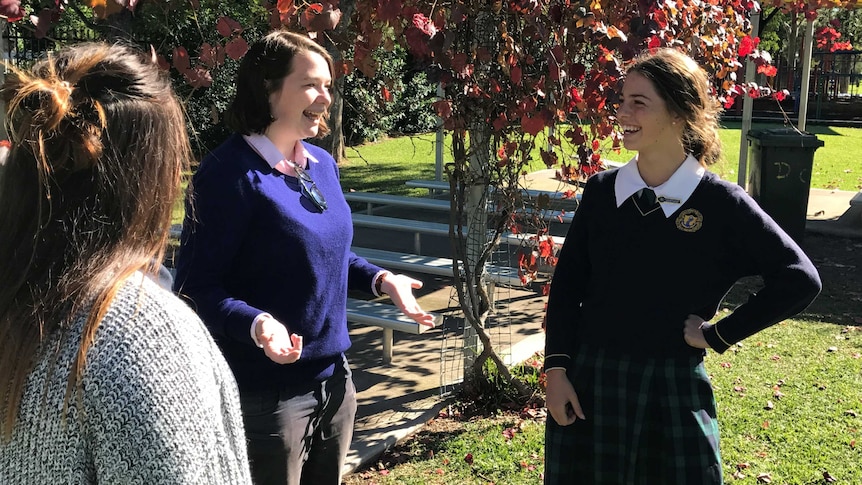 Animated Australian UN Ambassador for Youth speaking with St Philomena's School Captain in school yard under autumn tree