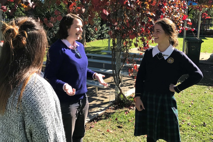 Animated Australian UN Ambassador for Youth speaking with St Philomena's School Captain in school yard under autumn tree