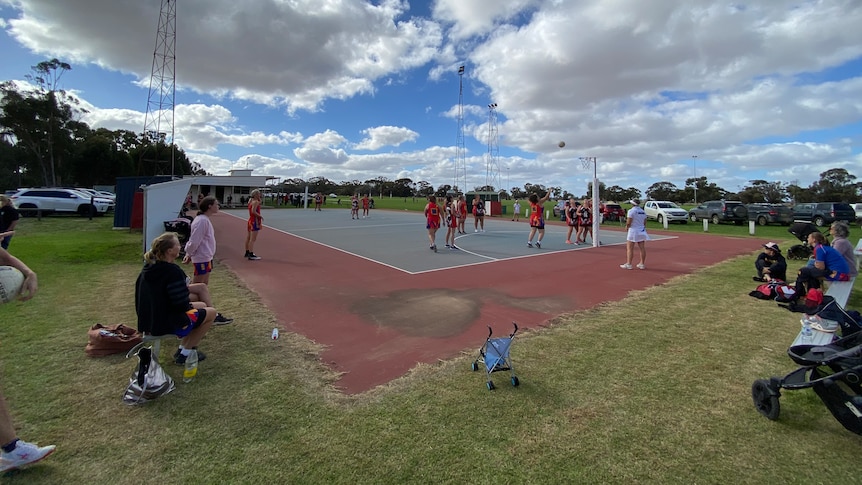 A netball match takes place on a partly cloudy day in regional Victoria