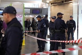 Police stand at the site where a man stabbed a French soldier in the neck.