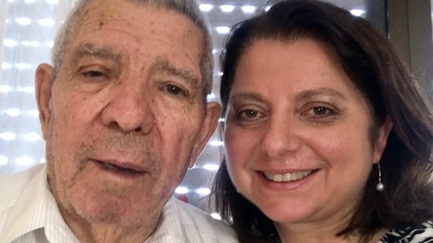 Natalia in a photograph with her father, in front of a window, smiling for the camera.